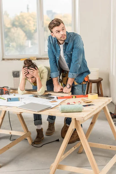 Verärgertes junges Paar lehnt sich bei Reparatur mit Werkzeug an Tisch — Stockfoto