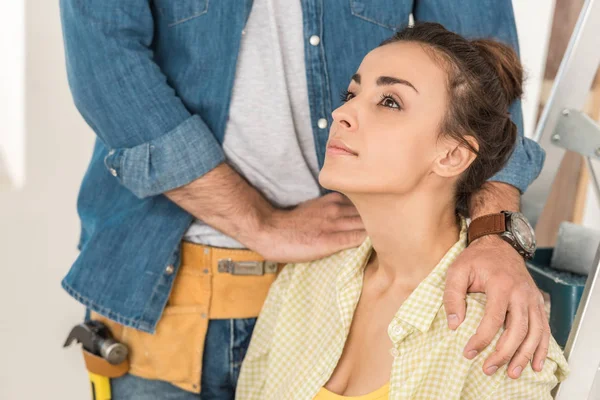 Cropped shot of man with toolbelt touching shoulders of pensive wife during repairment — Stock Photo