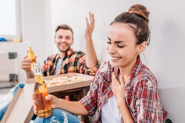 Happy young couple drinking beer and laughing during break in repairment — Stock Photo