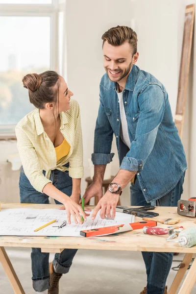 Glückliches junges Paar diskutiert Bauplan bei Renovierung — Stockfoto