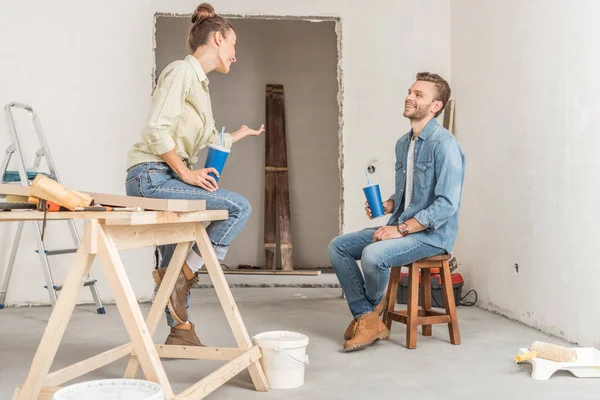 Glückliches junges Paar hält Pappbecher in der Hand und redet während der Reparatur — Stockfoto
