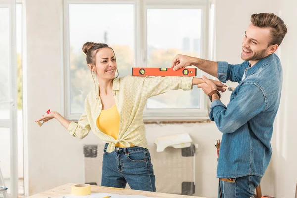 Glückliches junges Paar, das während der Reparatur Spaß mit Werkzeugen hat — Stockfoto