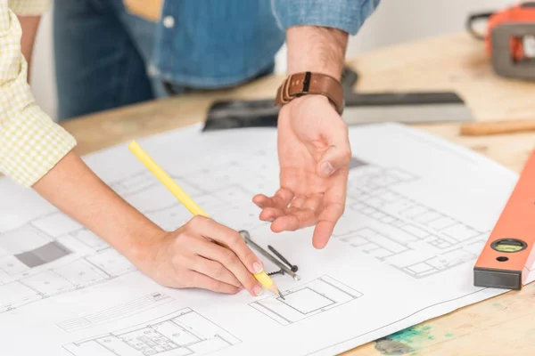 Close-up partial view of young couple pointing at marking blueprint during renovation — Stock Photo