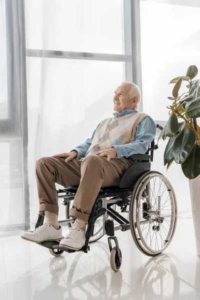 Anciano sonriente sentado en silla de ruedas en un hogar de ancianos - foto de stock