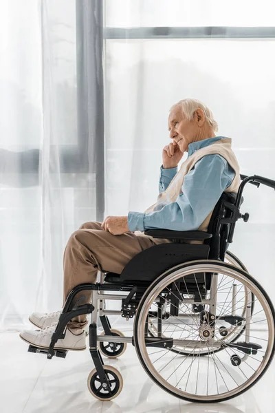Заботливый грустный пожилой мужчина сидит в инвалидной коляске в доме престарелых — стоковое фото