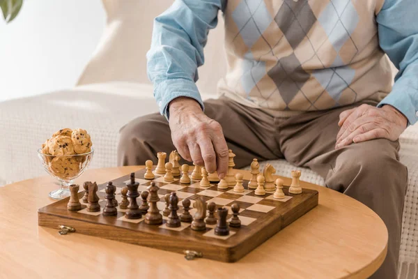 Close up of senior man sitting on sofa and playing chess — Stock Photo