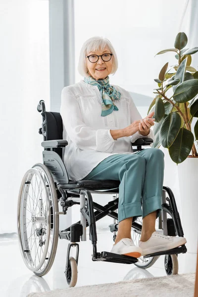 Alegre anciana sentada en silla de ruedas en un hogar de ancianos - foto de stock