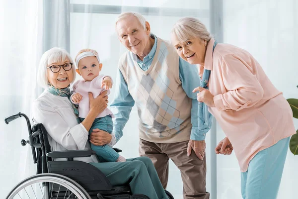 Счастливые пожилые люди с малышом в доме престарелых — стоковое фото