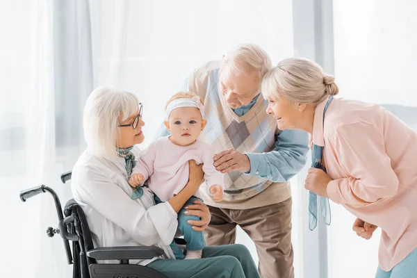 Щасливі люди похилого віку грають з малюком у будинку престарілих — стокове фото
