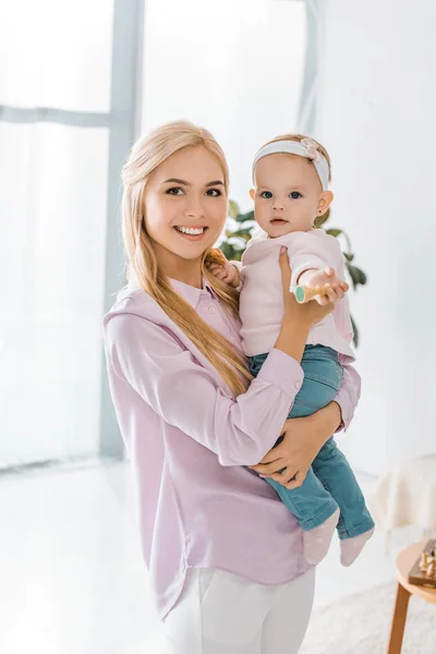 Jovem sorrindo mãe segurando criança filha com figura de xadrez na mão — Fotografia de Stock