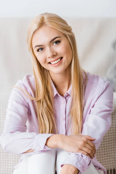 Jeune femme souriante avec de longs cheveux blonds regardant la caméra — Photo de stock