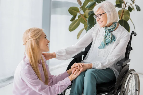 Jeune femme assise près d'une femme âgée en fauteuil roulant — Photo de stock