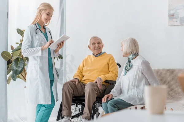 Joven doctora sonriente examinando a personas mayores en un asilo de ancianos — Stock Photo