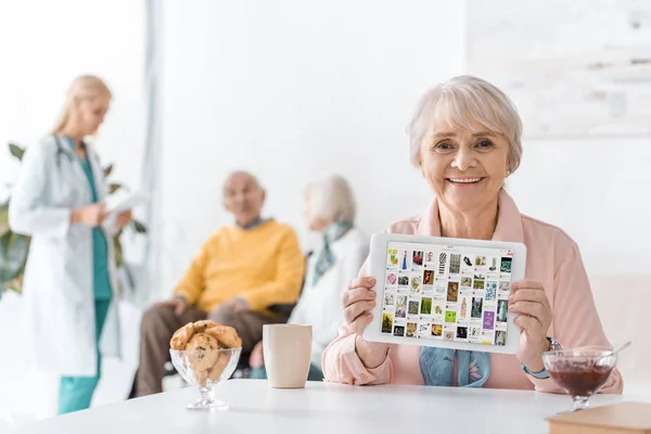 Seniorin zeigt Pinterest-App auf digitalem Tablet-Bildschirm im Pflegeheim — Stockfoto