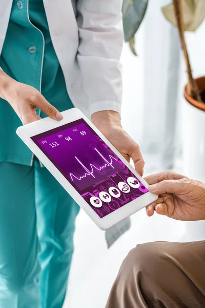 Primer plano en el médico y las manos del paciente sosteniendo tableta digital con cardiograma en la pantalla - foto de stock
