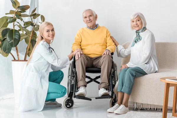 Joven doctora sentada con pacientes mayores en la clínica - foto de stock