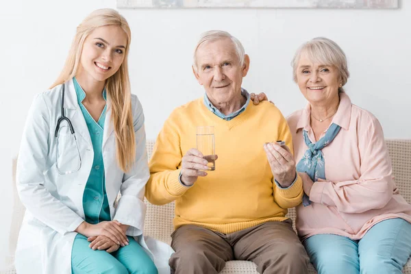 Young female doctor giving medicine to senior patients — Stock Photo