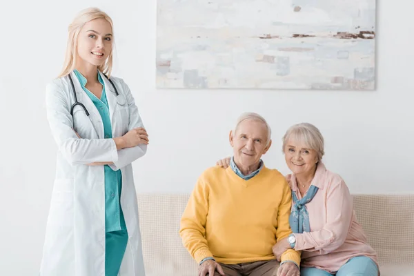 Medico donna in piedi vicino a pazienti anziani sorridenti in clinica — Foto stock