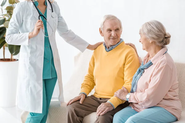Female doctor standing near senior patients in clinic — Stock Photo