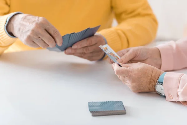 Primer plano de las personas mayores jugando a las cartas en la mesa blanca - foto de stock