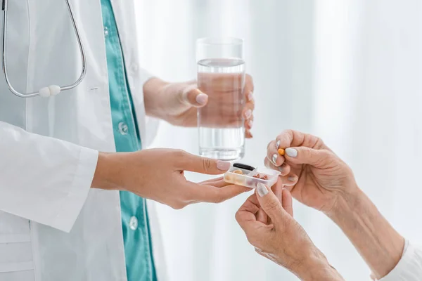 Close up of young female doctor giving pills to senior woman — Stock Photo