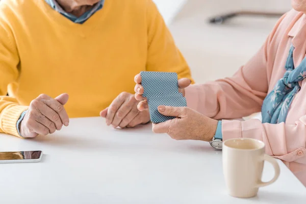 Close up of senior people playing cards on white table — Stock Photo