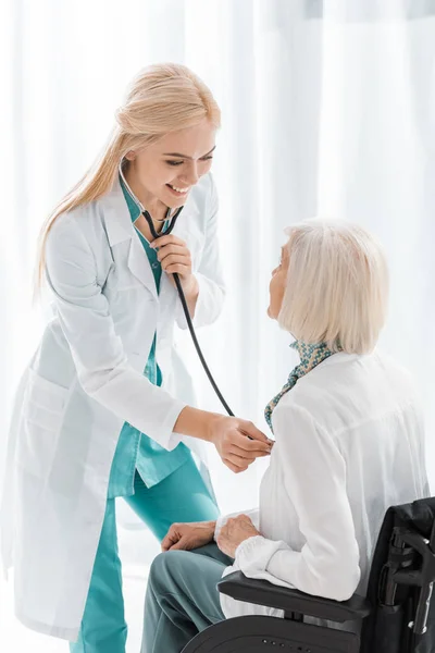 Улыбающаяся женщина-врач осматривает со стетоскопом пожилую женщину — стоковое фото