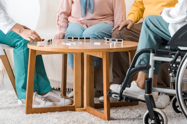 Médico jogando dominó na mesa com pacientes seniores — Fotografia de Stock