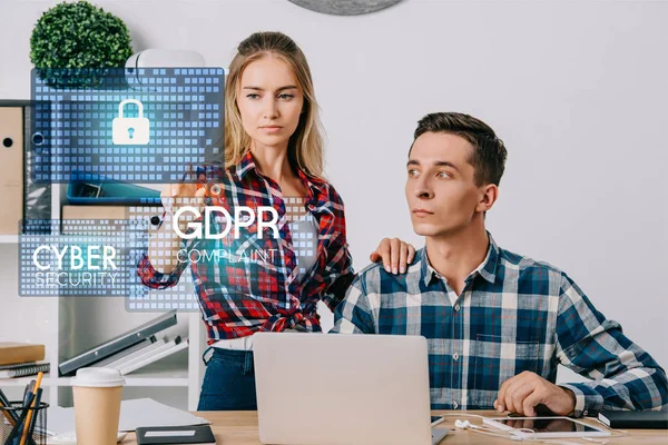 Businessman looking at female colleague pointing at cyber security signs at workplace in office, web security concept — Stock Photo