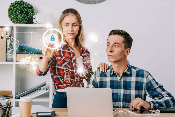 Geschäftsmann schaut Kollegin an und zeigt auf Cyber-Sicherheitsschilder am Arbeitsplatz im Büro, Web-Sicherheitskonzept — Stockfoto