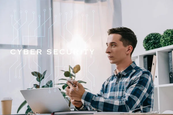 Seitenansicht Geschäftsmann mit Smartphone am Arbeitsplatz sitzend mit Laptop im Büro, Cyber-Sicherheitskonzept — Stockfoto