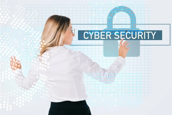 Back view of businesswoman in eyeglasses pointing at cyber security sign isolated on white, information security concept — Stock Photo