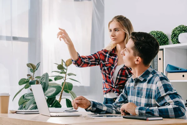 Businessman looking at female colleague gesturing at workplace in office — Stock Photo