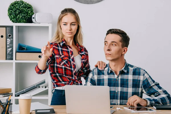 Hombre de negocios mirando a una colega haciendo gestos en el lugar de trabajo en la oficina - foto de stock