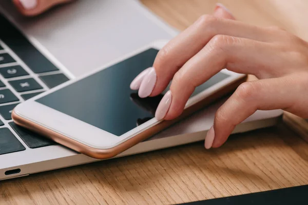 Обрізаний знімок бізнес-леді, використовуючи смартфон на робочому місці з ноутбуком — стокове фото