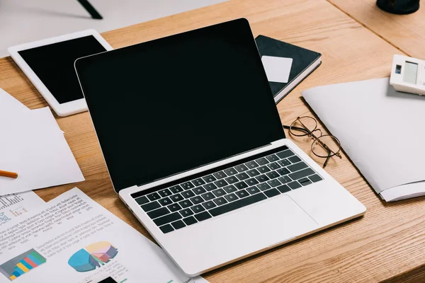 Vue rapprochée du lieu de travail avec ordinateur portable, tablette, lunettes et papiers — Photo de stock