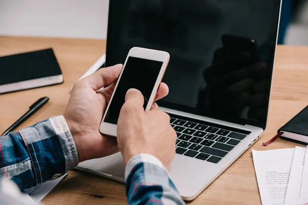 Plan recadré de l'homme d'affaires en utilisant smartphone sur le lieu de travail avec ordinateur portable — Photo de stock