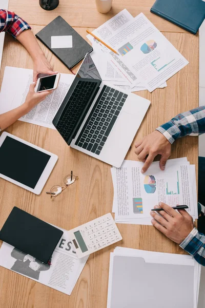 Fotografía recortada de empresarios que trabajan en el lugar de trabajo con dispositivos y documentos digitales - foto de stock