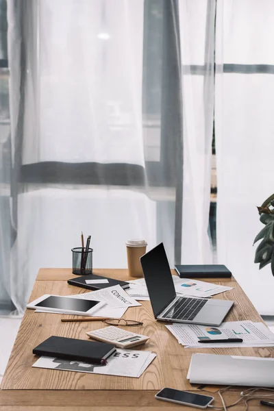 Vue rapprochée du lieu de travail avec ordinateur portable, table, documents et café à emporter — Photo de stock