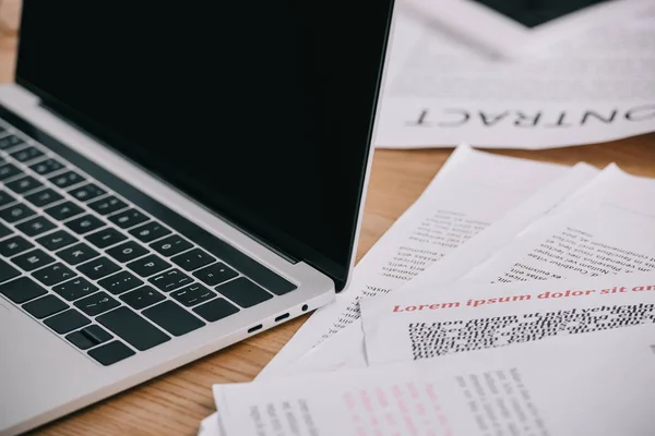 Nahaufnahme von Laptop mit leerem Bildschirm und Papieren auf hölzerner Tischplatte — Stockfoto