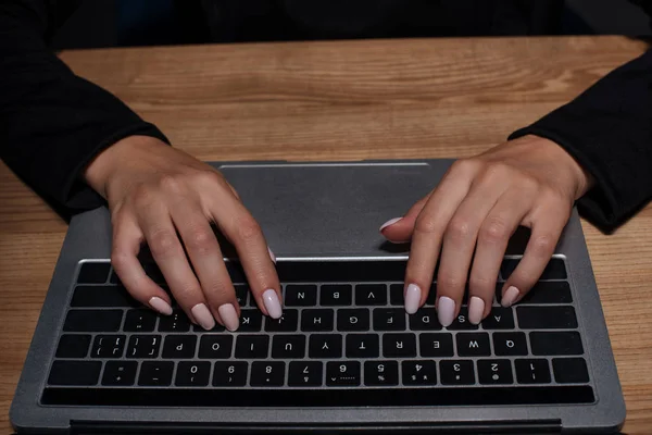 Partial view of female hacker using digital laptop at wooden tabletop — Stock Photo