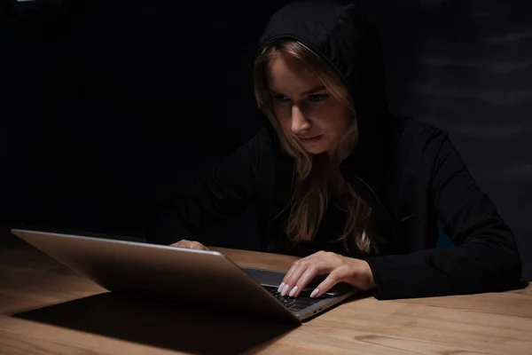 Ritratto di donna con cappuccio nero con computer portatile, concetto di sicurezza informatica — Foto stock