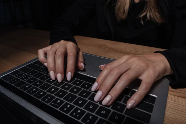 Vista parcial del hacker femenino usando portátil digital en la mesa de madera - foto de stock