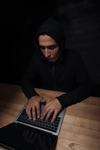 Concentrated hacker using laptop at wooden tabletop, cuber security concept — Stock Photo