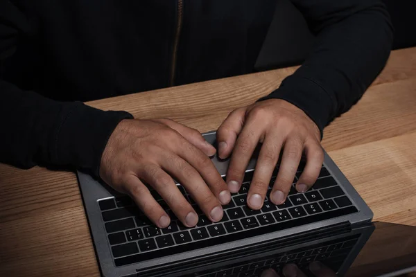 Cropped shot of hacker using laptop at wooden tabletop, cuber security concept — Stock Photo