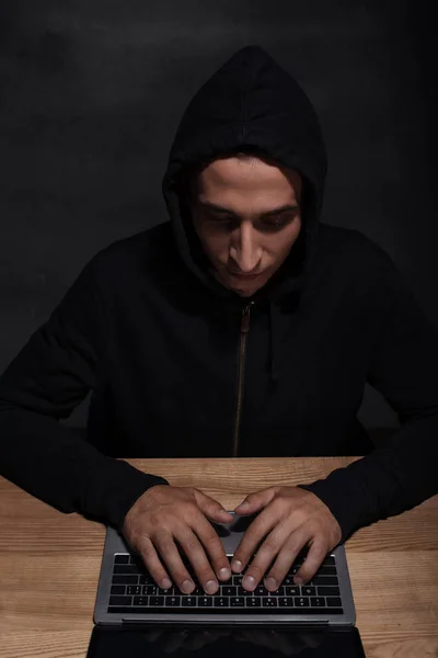 Hacker com capuz preto usando laptop, conceito de segurança cuber — Fotografia de Stock