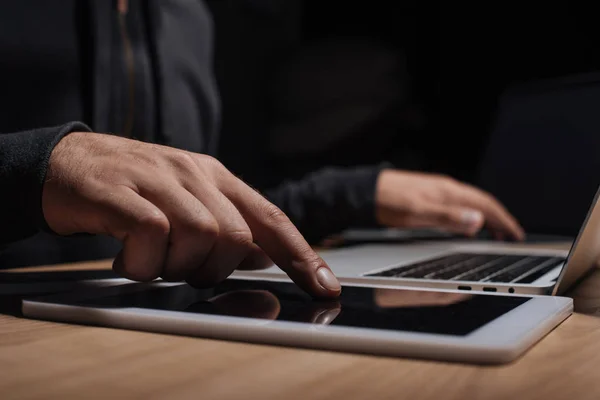 Recortado tiro de hacker masculino utilizando el ordenador portátil y tableta, concepto de seguridad cibernética - foto de stock