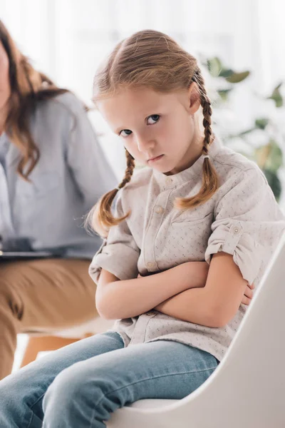 Cropped shot of psychologist talking to depressed child with crossed arms while she looking at camera — Stock Photo