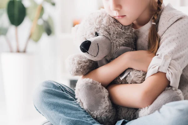 Cropped shot of depressed little child embracing her teddy bear — Stock Photo