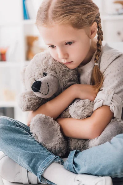 Close-up portrait of depressed little child embracing her teddy bear — Stock Photo